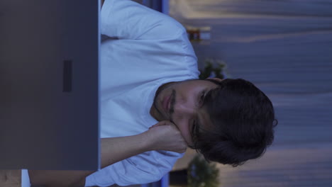 Vertical-video-of-Unhappy-man-using-laptop-laptop-at-night.-It's-not-in-a-good-mood.